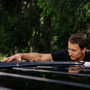 Man installing monocrystalline solar panel on VW California roof outdoors