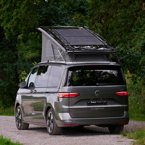 VW T7 Beach camper van with pop-up roof and solar panel parked on a forest road