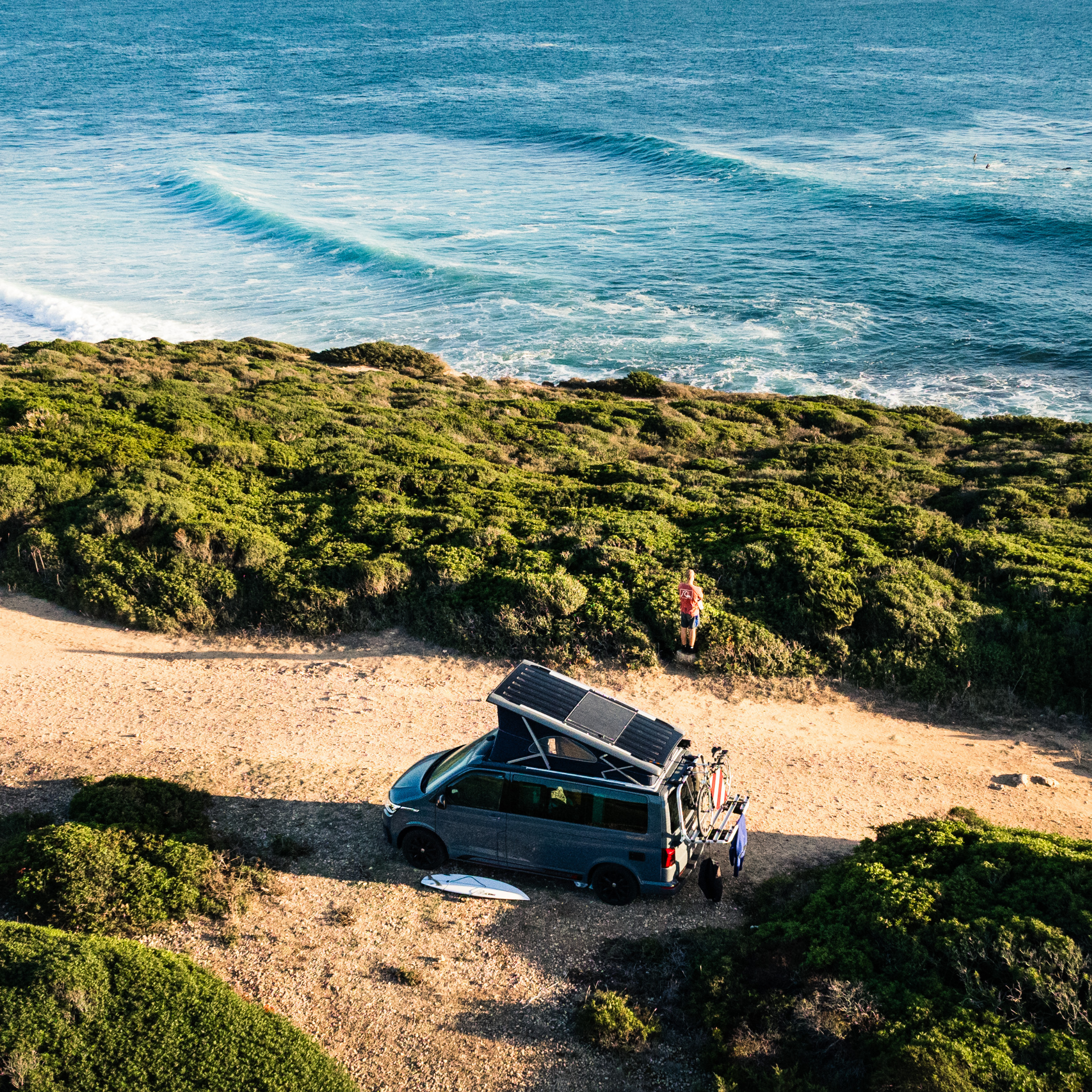 VW California Camper mit geöffnetem Aufstelldach und Solarpanel am Meer – CALIFAKTUR Lithium-Autarkiepaket mit SaftkistePRO 170 Ah und Victron Orion XS für maximale Energieautarkie im Camper.